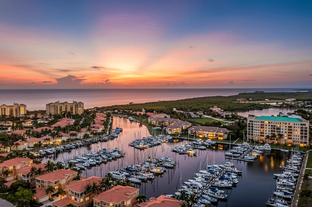 An aerial view of a marina filled with boats surrounded by residential buildings at sunset — 2060 MATECUMBE KEY ROAD UNIT 2106, PUNTA GORDA, FL
