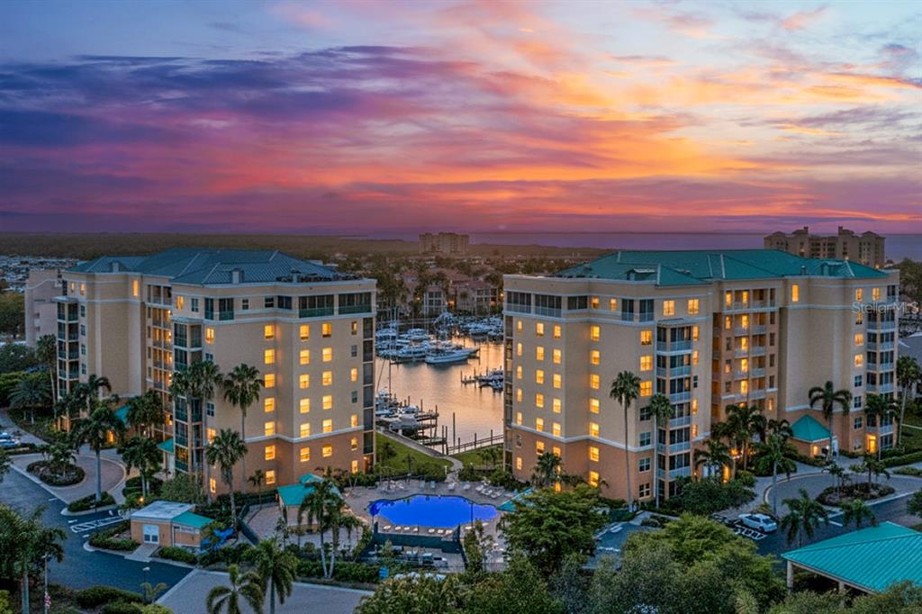 An aerial view of two multi-story residential buildings flanking a marina and a swimming pool — 2060 MATECUMBE KEY ROAD UNIT 2106, PUNTA GORDA, FL