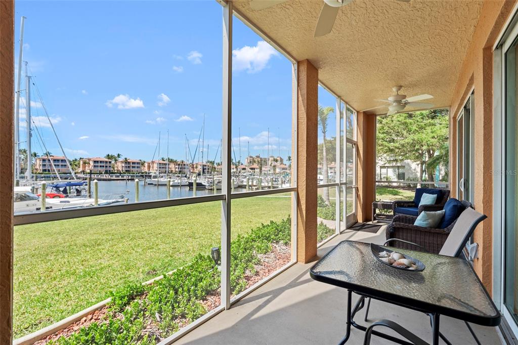 A screened-in patio with outdoor furniture overlooks a marina filled with sailboats and residential buildings — 2060 MATECUMBE KEY ROAD UNIT 2106, PUNTA GORDA, FL