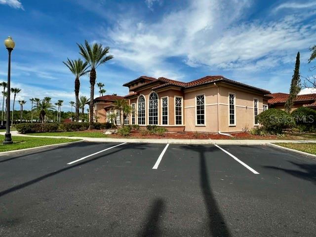 A tan-colored building with a tiled roof sits behind an empty parking lot — 5554 METROWEST BOULEVARD UNIT 212, ORLANDO, FL
