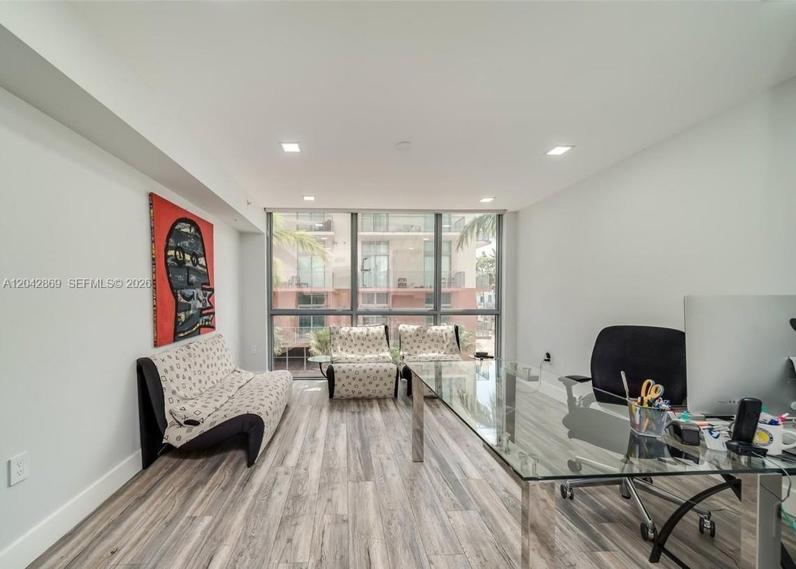 A home office features a glass desk, a patterned sofa, two chairs, and floor-to-ceiling windows — 140 S Dixie Hwy, Hollywood FL 33020, HOLLYWOOD, FL