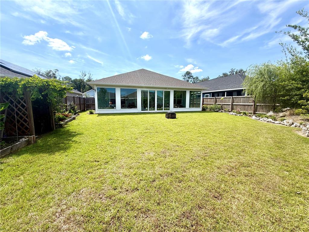 A backyard view of a house with a large glass-enclosed sunroom and wooden fencing — 1464 SW 66TH WAY, GAINESVILLE, FL