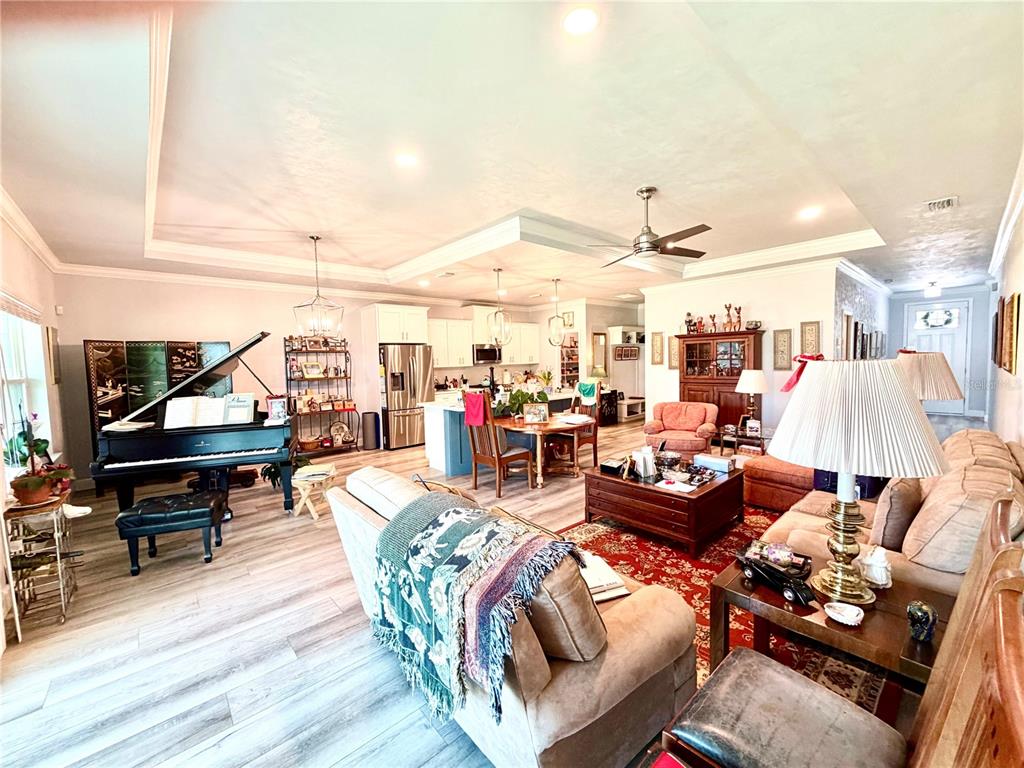 An open-concept living room and kitchen featuring a grand piano, wood-look flooring, and recessed lighting — 1464 SW 66TH WAY, GAINESVILLE, FL