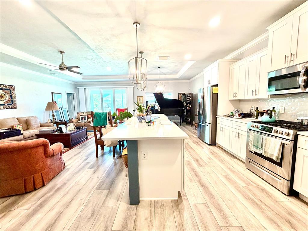 A kitchen with a large white island and stainless steel appliances opens to a living area — 1464 SW 66TH WAY, GAINESVILLE, FL