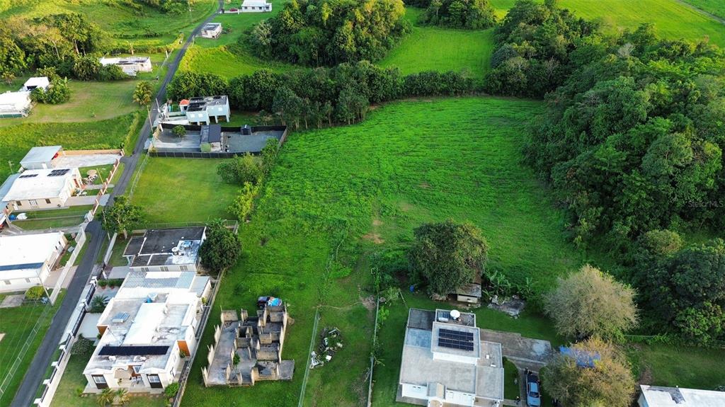 An aerial view shows a large, grassy vacant lot surrounded by residential houses and trees — HC3 BOX 4278, SABANA HOYOS, PR