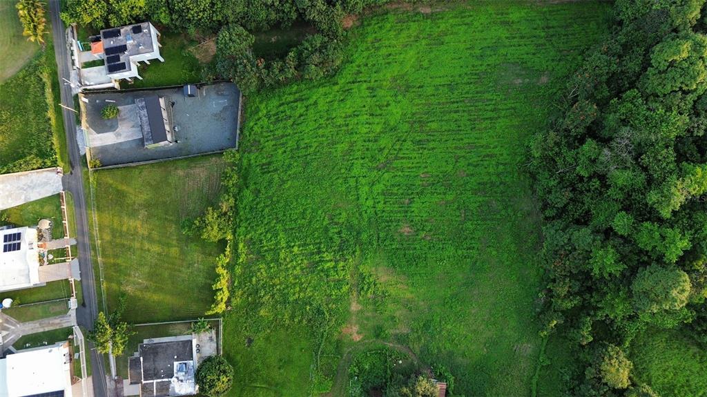 An aerial view shows a large, grassy vacant lot adjacent to several residential properties — HC3 BOX 4278, SABANA HOYOS, PR