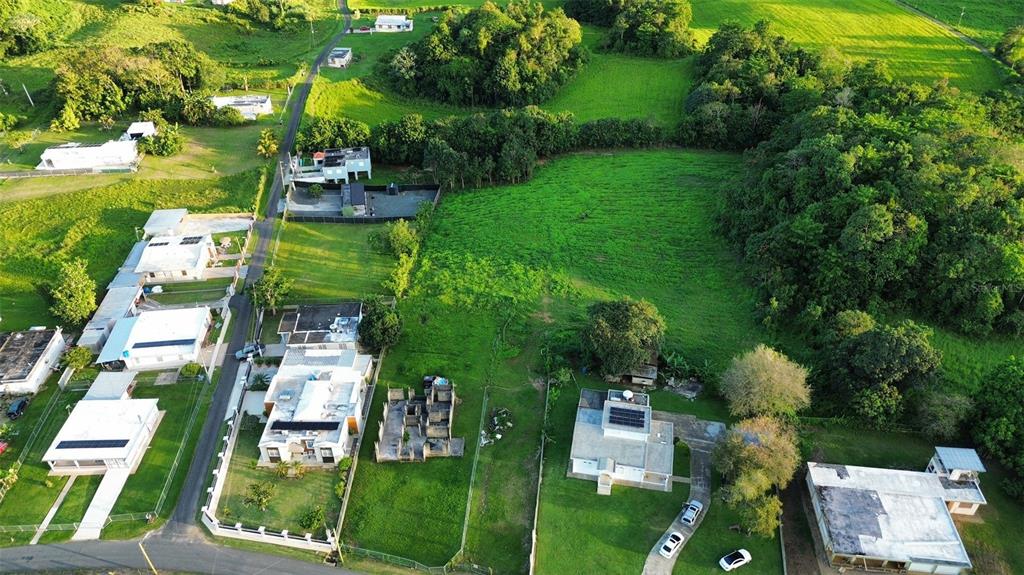An aerial view shows a residential neighborhood with houses, green lawns, and surrounding wooded areas — HC3 BOX 4278, SABANA HOYOS, PR