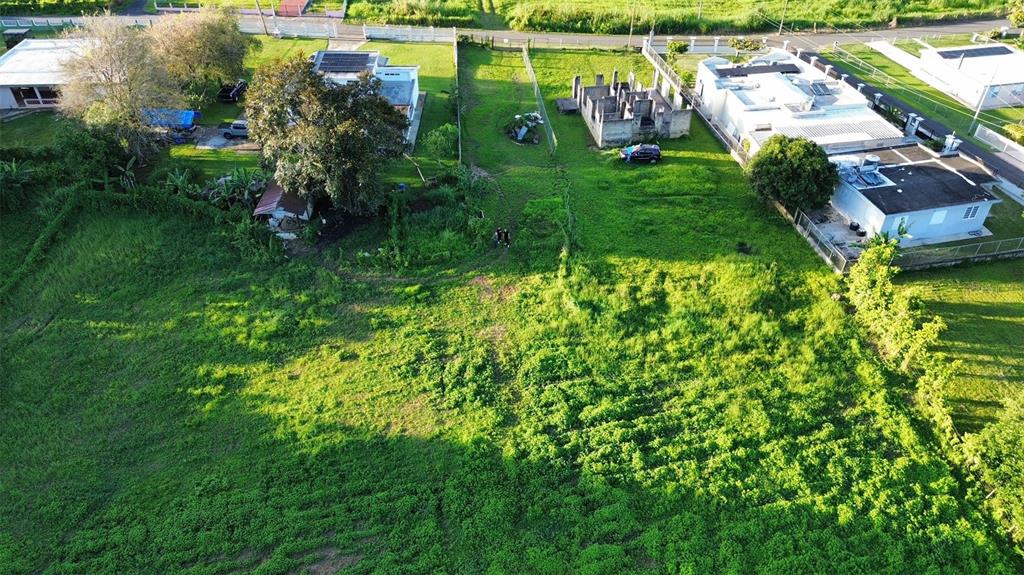 An aerial view shows a large grassy lot situated between several residential houses — HC3 BOX 4278, SABANA HOYOS, PR
