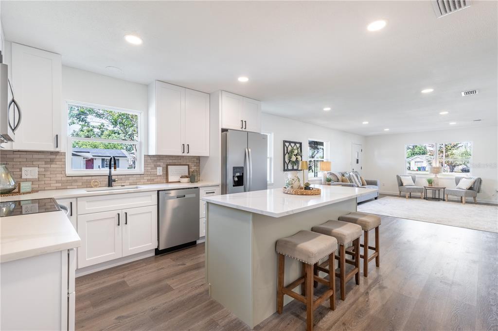 A modern kitchen with white cabinets, a central island, and stainless steel appliances — 1201 SHERMAN AVENUE, TAVARES, FL