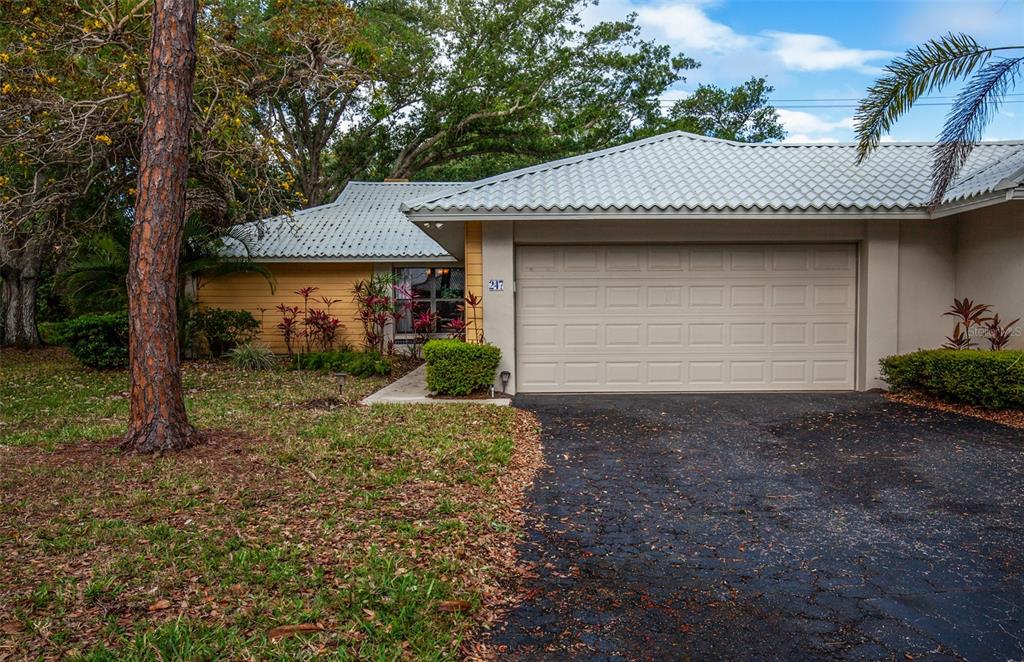 A single-story house with a light-colored metal roof, tan siding, and a two-car garage — 247 SOUTHAMPTON LANE UNIT 272, VENICE, FL