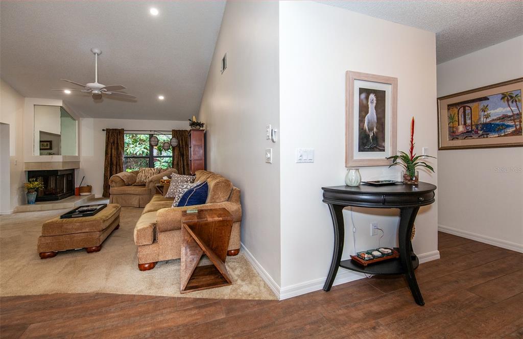 A living room with a fireplace and sofa transitions into a foyer with a console table — 247 SOUTHAMPTON LANE UNIT 272, VENICE, FL