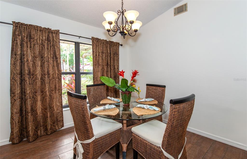 A dining room features a glass-topped table, four wicker chairs, and brown patterned curtains — 247 SOUTHAMPTON LANE UNIT 272, VENICE, FL