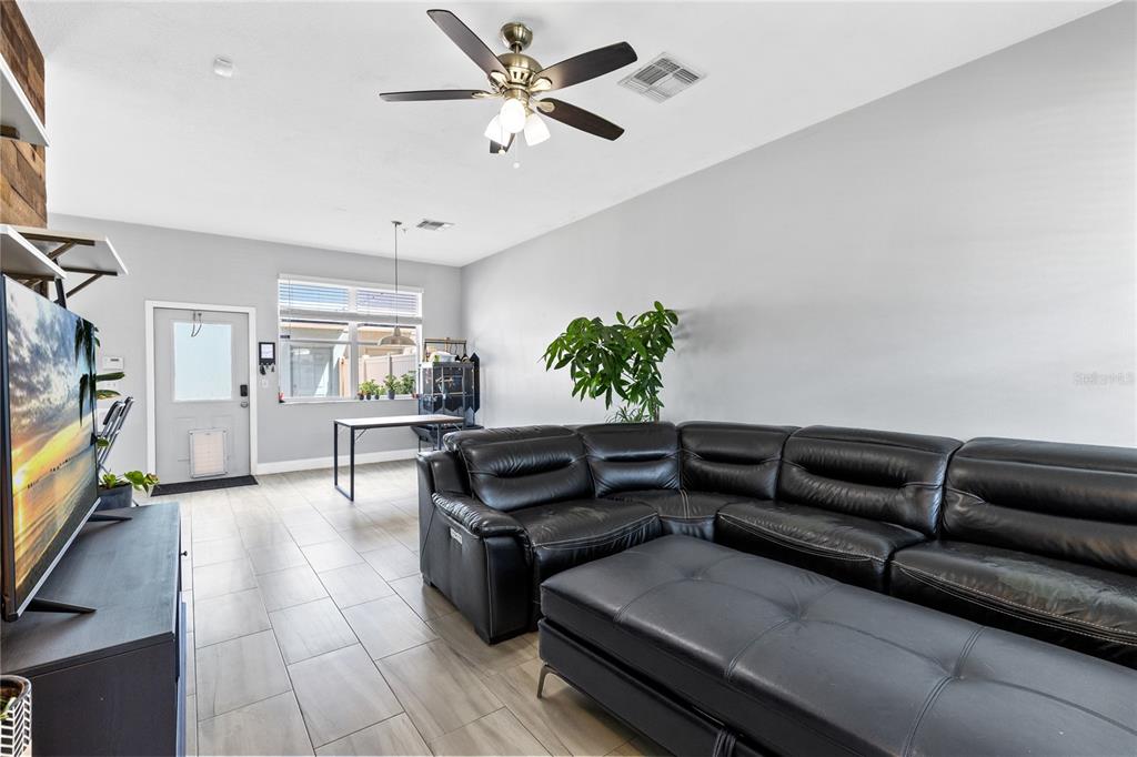 A living room features a large black sectional sofa, tile flooring, and a ceiling fan — 6187 CHAPLEDALE DRIVE, ORLANDO, FL