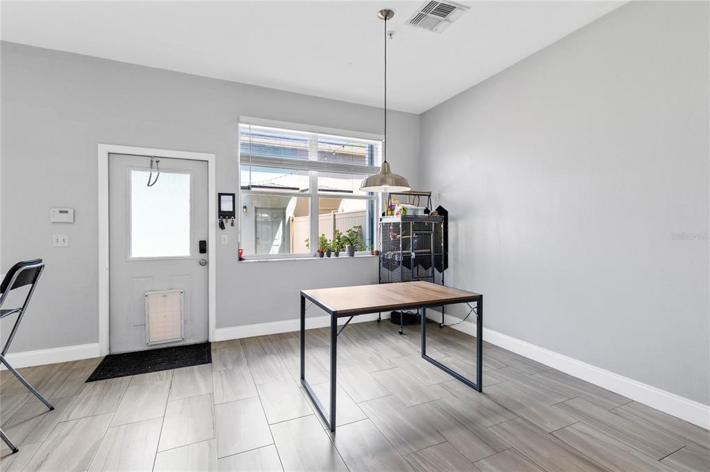A dining area features gray tile flooring, light gray walls, a window, and a metal table — 6187 CHAPLEDALE DRIVE, ORLANDO, FL