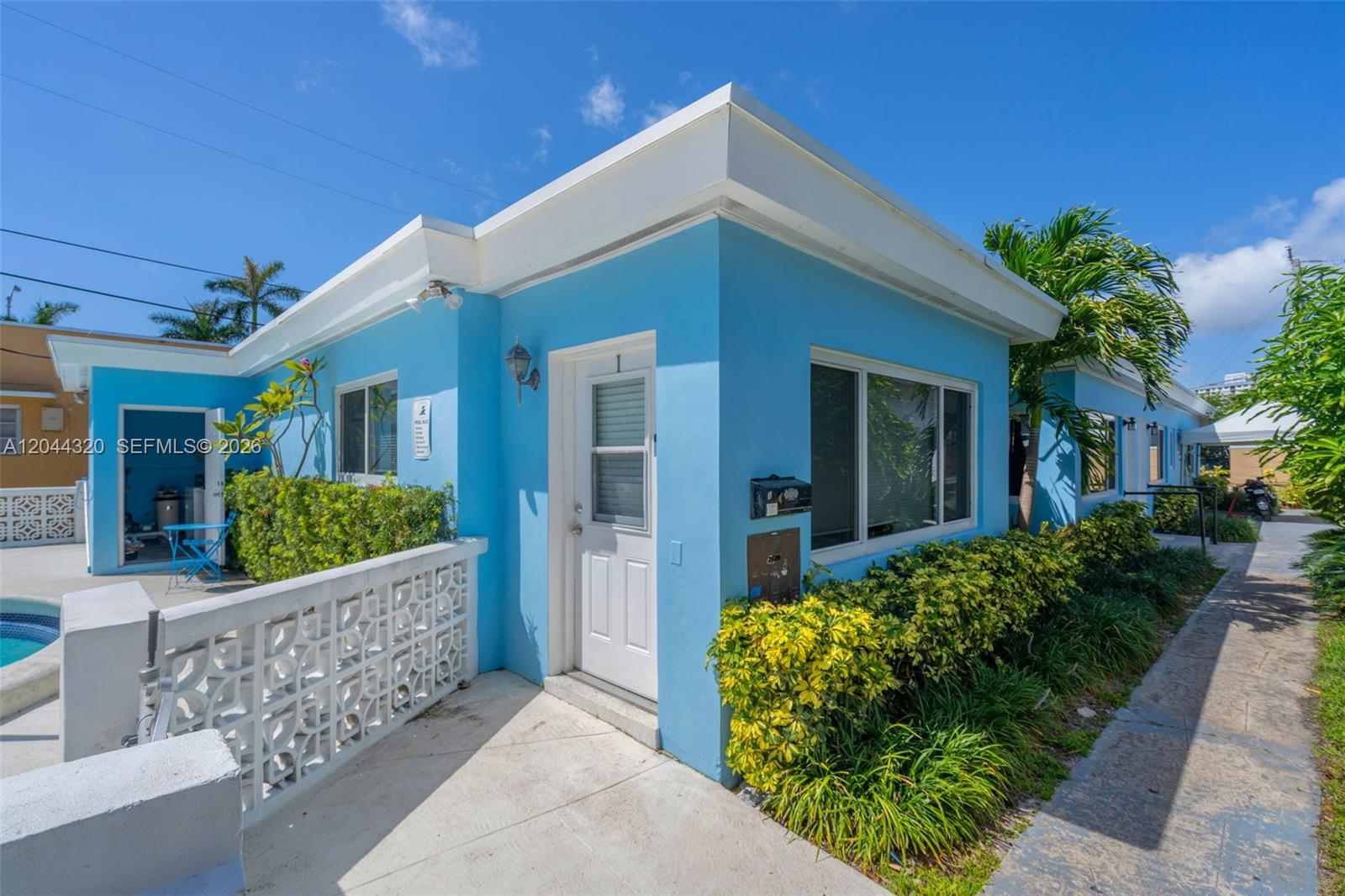 A bright blue exterior building features a white door, a window, and a decorative wall — 2120 Biarritz Dr # 1, Miami Beach FL 33141, MIAMI BEACH, FL