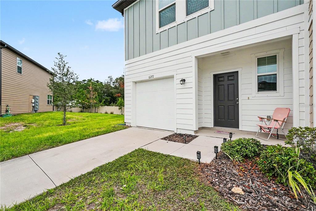 A two-story house exterior features a white garage, a dark front door, and a lawn — 6272 BUCKET COURT, GIBSONTON, FL