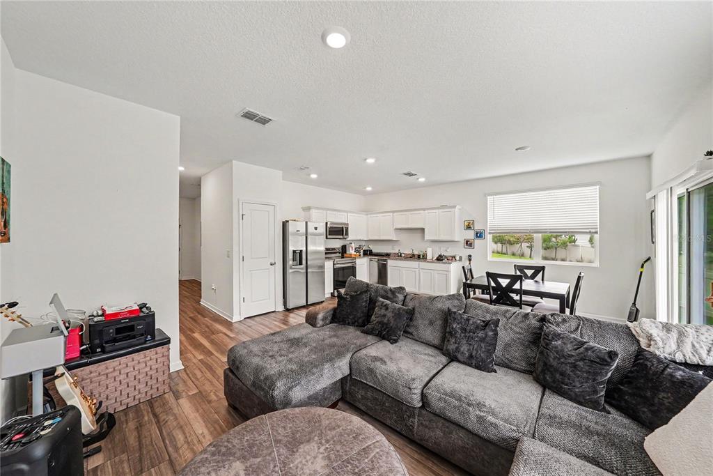 An open-concept living room and kitchen featuring a gray sectional sofa and wood flooring — 6272 BUCKET COURT, GIBSONTON, FL