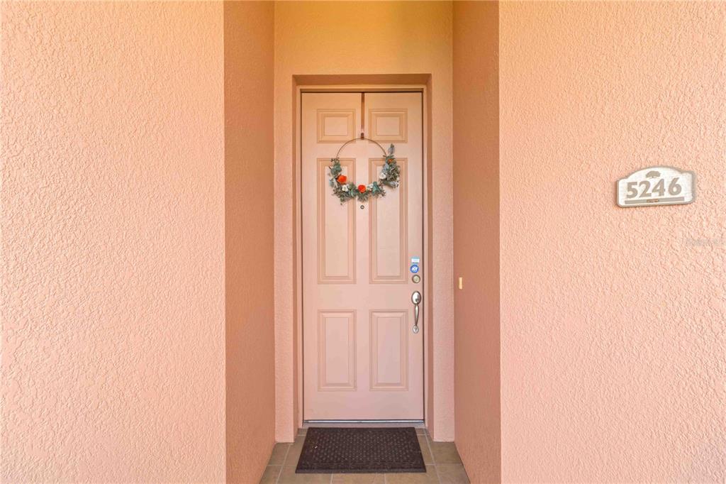 A light pink exterior wall features a front door with a wreath and house numbers — 5246 MANORWOOD DRIVE UNIT 4C, SARASOTA, FL
