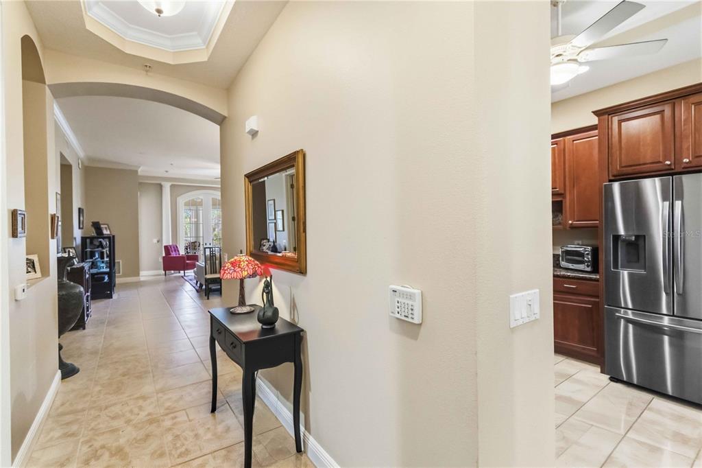 A hallway with tile flooring leads to a living area, with a kitchen visible nearby — 5246 MANORWOOD DRIVE UNIT 4C, SARASOTA, FL