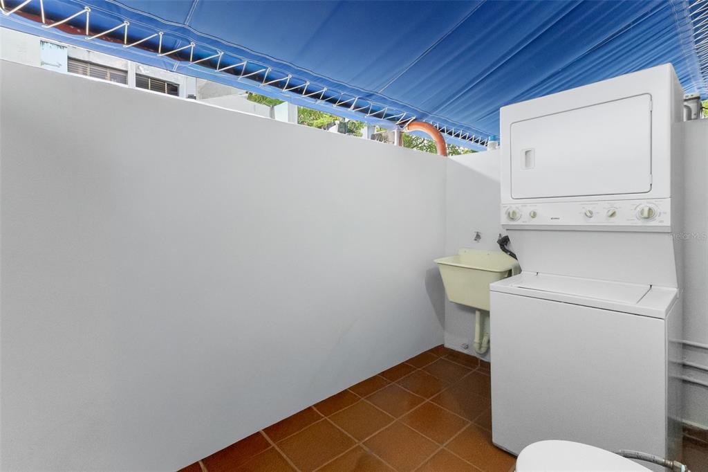 An outdoor laundry area features a stacked washer and dryer next to a utility sink — 111 CALLE DONCELLA UNIT TH2, SAN JUAN, PR