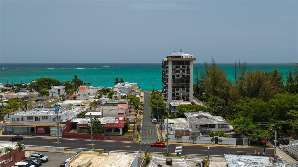 An aerial view shows a coastal street with residential buildings and a tall apartment complex — 111 CALLE DONCELLA UNIT TH2, SAN JUAN, PR