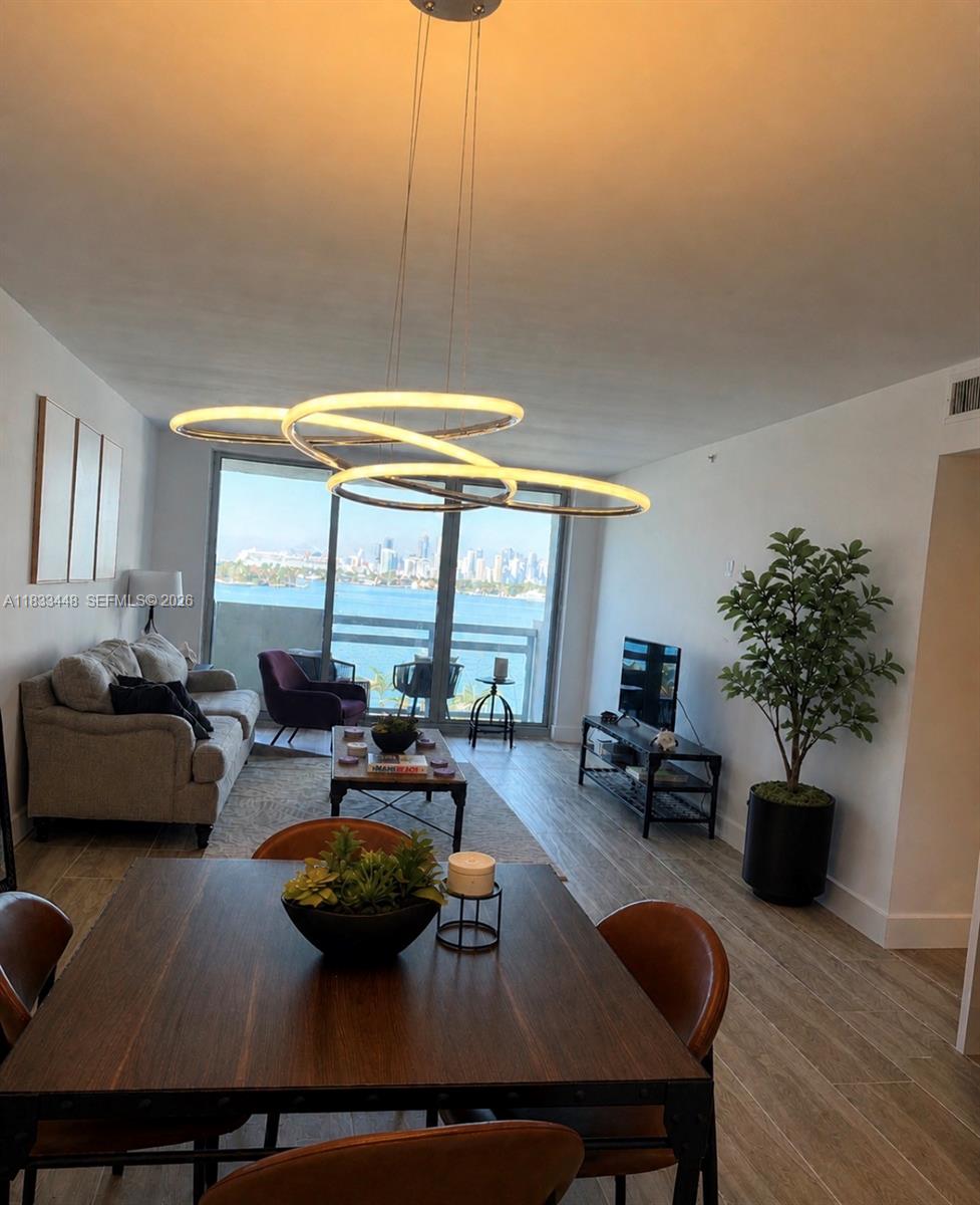 A bedroom features a bed, dark wood furniture, light wood-look flooring, and a waterfront view — 1500 Bay Rd # 724S, Miami Beach FL 33139, MIAMI BEACH, FL