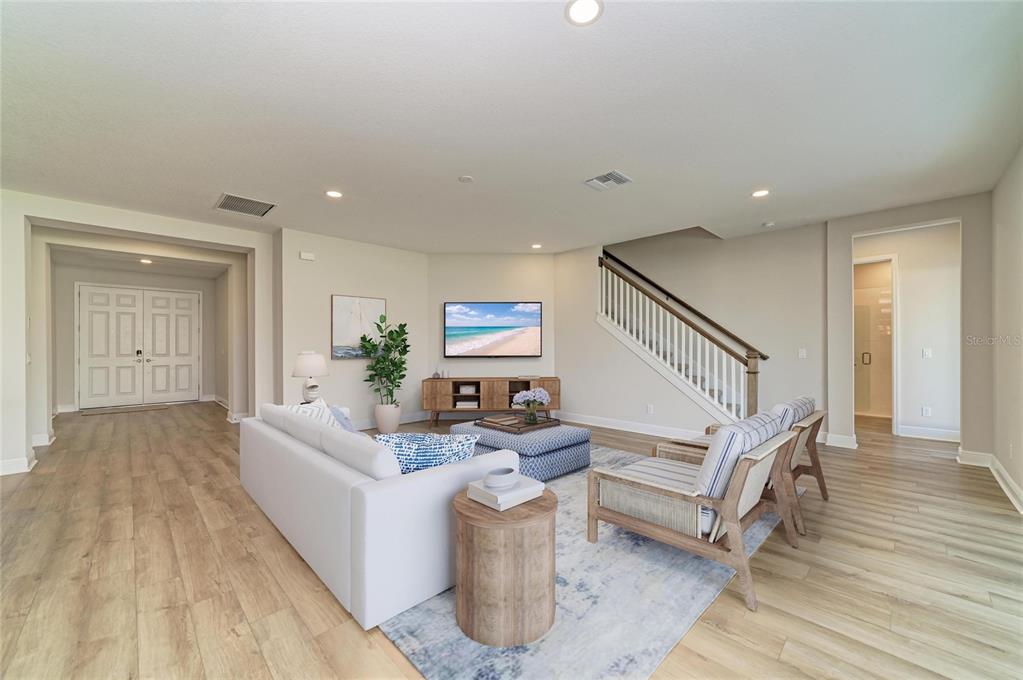 A living room features light wood flooring, a white sofa, two armchairs, and a staircase — 33882 TWILIGHT SEA PLACE, DADE CITY, FL