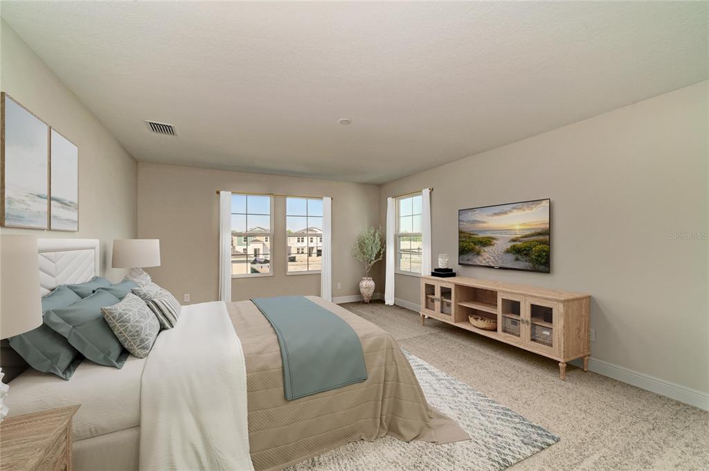 A bedroom features a bed, a wooden media console, and windows overlooking a construction site — 33882 TWILIGHT SEA PLACE, DADE CITY, FL