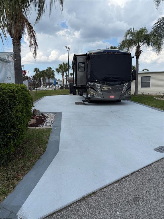 A large recreational vehicle is parked on a paved concrete pad next to a house — 9000 US HWY 192 UNIT 786, CLERMONT, FL