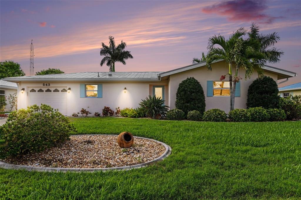 A single-story house with a metal roof, light-colored stucco, and a landscaped front yard — 543 BELVEDERE COURT, PUNTA GORDA, FL
