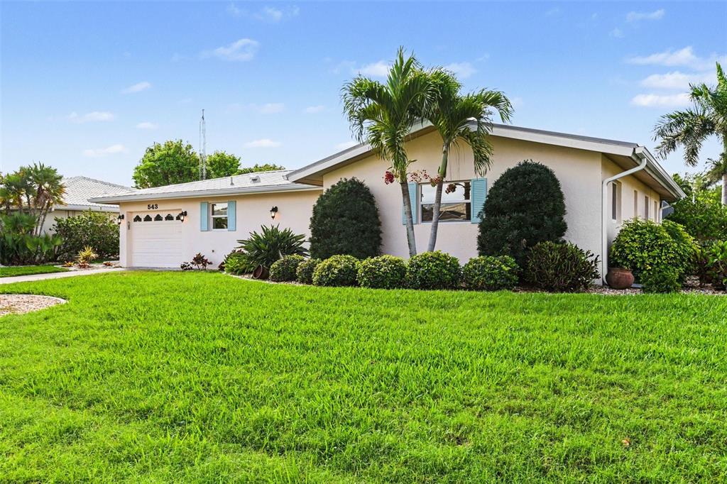 A single-story house with a light-colored exterior, a garage, and a manicured front lawn — 543 BELVEDERE COURT, PUNTA GORDA, FL