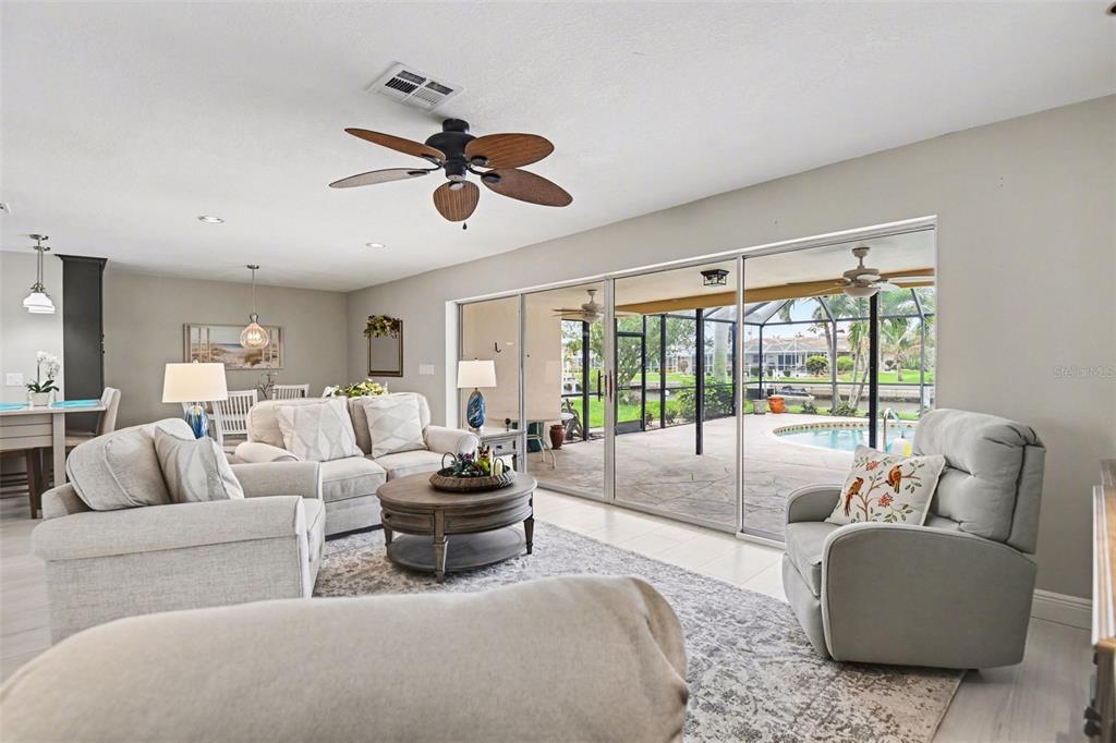 A living room with light furniture and a ceiling fan opens to a pool patio — 543 BELVEDERE COURT, PUNTA GORDA, FL