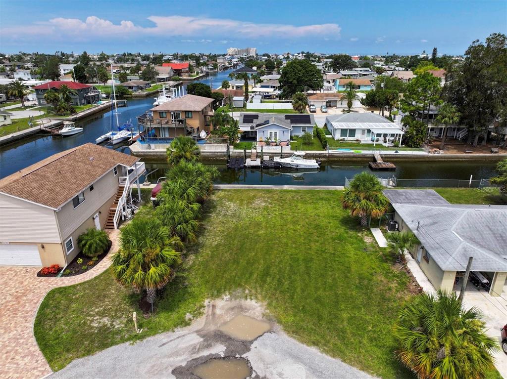 An aerial view shows a vacant waterfront lot situated between two houses with a canal — 13901 DULEY AVENUE, HUDSON, FL