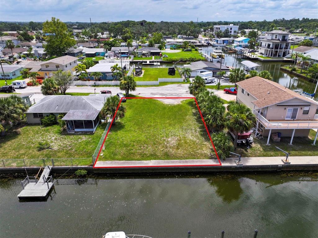 An aerial view shows a vacant waterfront lot outlined in red between two residential houses — 13901 DULEY AVENUE, HUDSON, FL