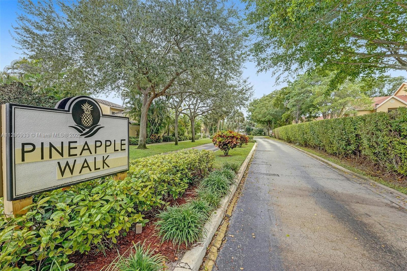 A sign for Pineapple Walk stands beside a paved road lined with trees and hedges — 22322 Pineapple Walk Drive, Boca Raton FL 33433, BOCA RATON, FL