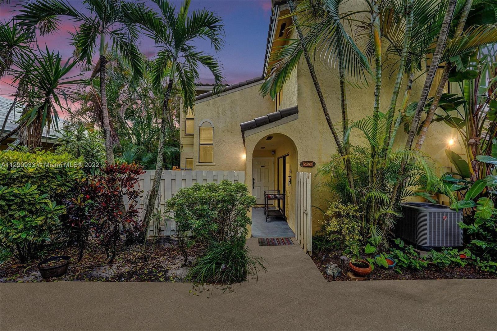 A yellow two-story townhouse exterior features a covered entryway, palm trees, and landscaping — 22322 Pineapple Walk Drive, Boca Raton FL 33433, BOCA RATON, FL