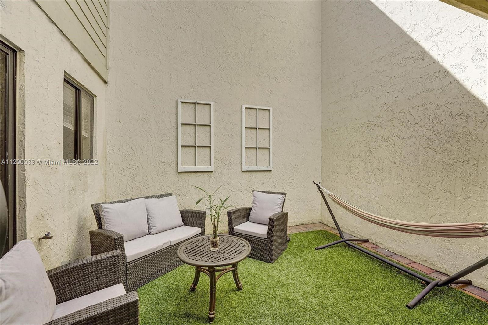 An outdoor patio features artificial turf, wicker furniture, a small table, and a hammock — 22322 Pineapple Walk Drive, Boca Raton FL 33433, BOCA RATON, FL
