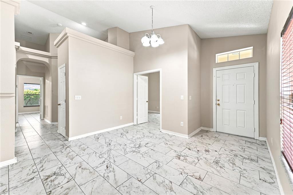 An entryway with white marble-look tile flooring, a chandelier, and a white front door — 2155 KAYLAS COURT, ORLANDO, FL