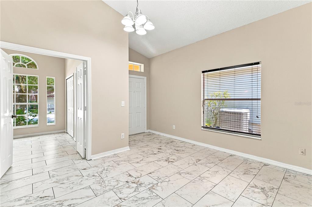 A room with white marble-look tile flooring, beige walls, a chandelier, and a large window — 2155 KAYLAS COURT, ORLANDO, FL
