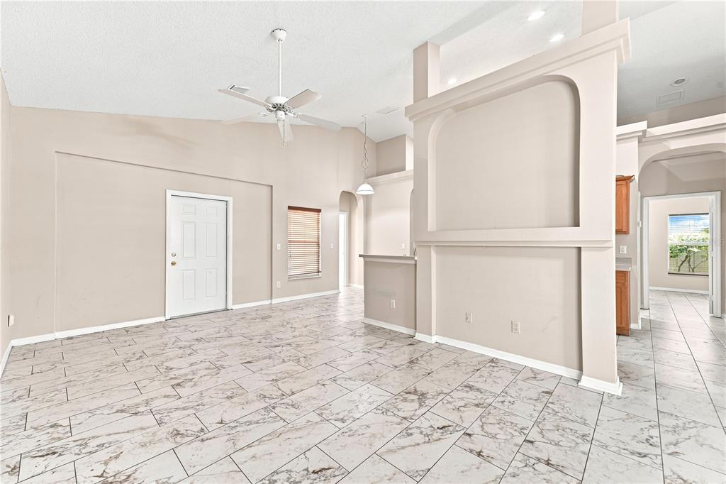 A spacious room features light-colored tile flooring, a vaulted ceiling with a fan, and an archway — 2155 KAYLAS COURT, ORLANDO, FL