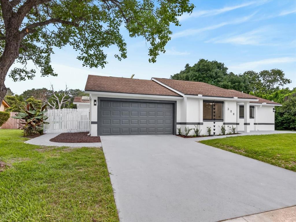 A single-story house with a gray garage door, white exterior, and a concrete driveway — 308 S SHADOW BAY DRIVE, ORLANDO, FL