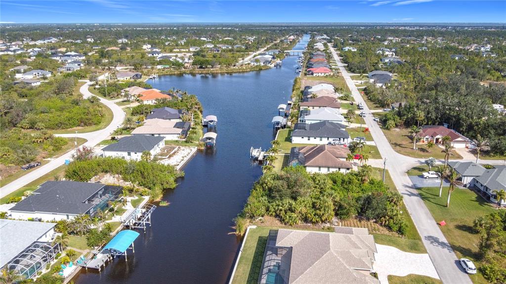 An aerial view shows houses lining a canal with boat docks and a paved road — 9177 SANTA LUCIA DRIVE, PORT CHARLOTTE, FL