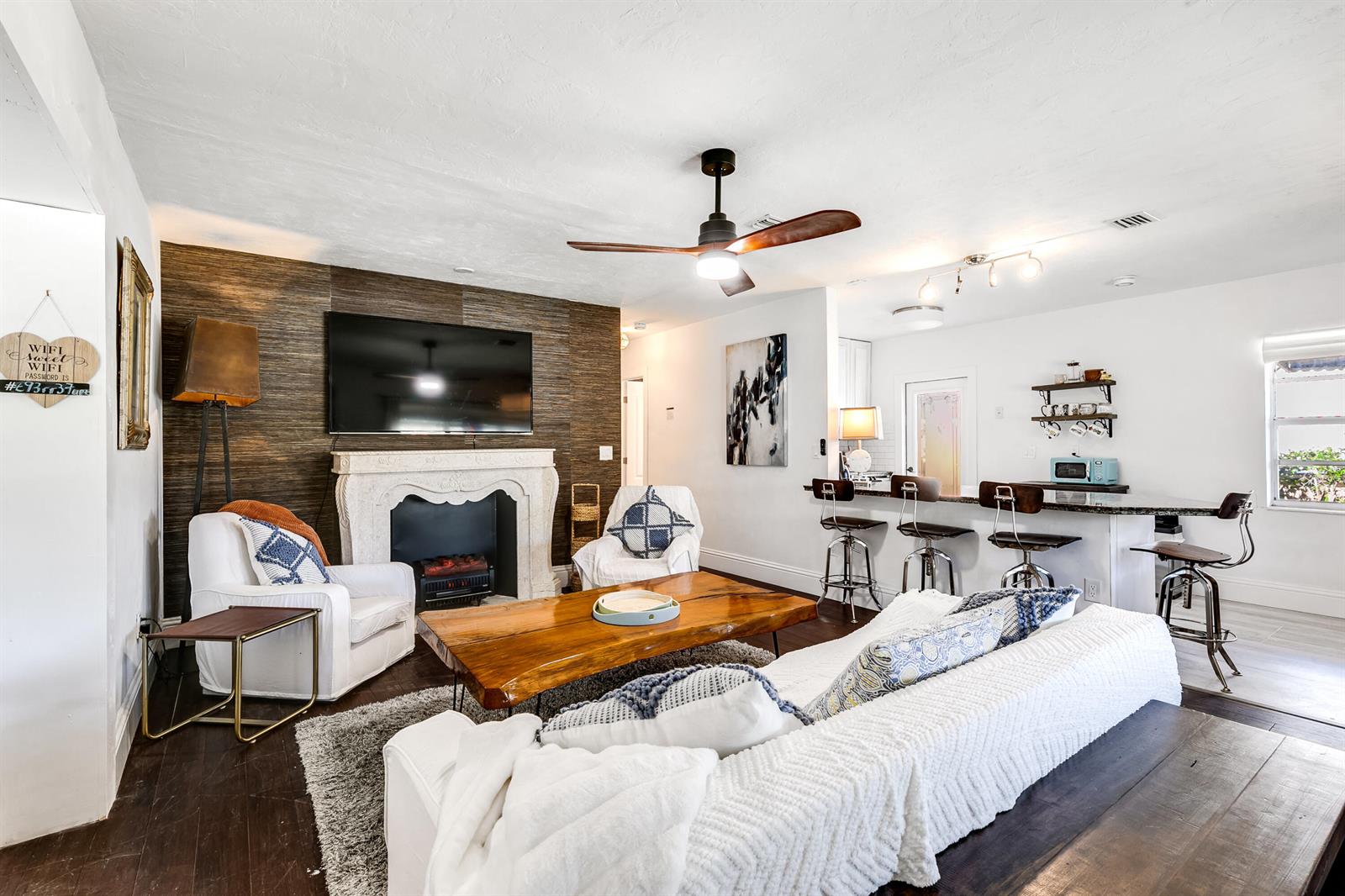 A living room features a fireplace with a TV, a wooden coffee table, and bar seating — 609 S Arnold Avenue, Lantana FL 33462, LANTANA, FL