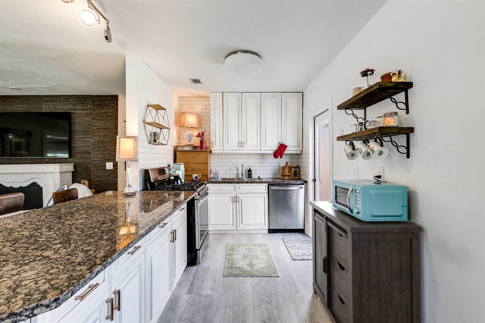 A kitchen features white cabinets, granite countertops, a stainless steel dishwasher, and a blue microwave — 609 S Arnold Avenue, Lantana FL 33462, LANTANA, FL