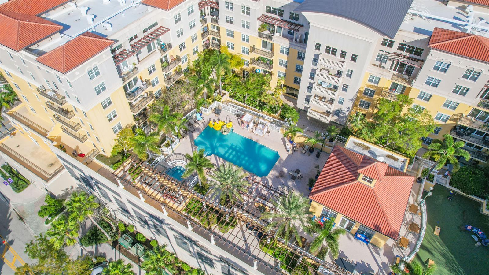 An aerial view of an apartment complex courtyard featuring a swimming pool and clubhouse — 101 Plaza Real S # 829, Boca Raton FL 33432, BOCA RATON, FL