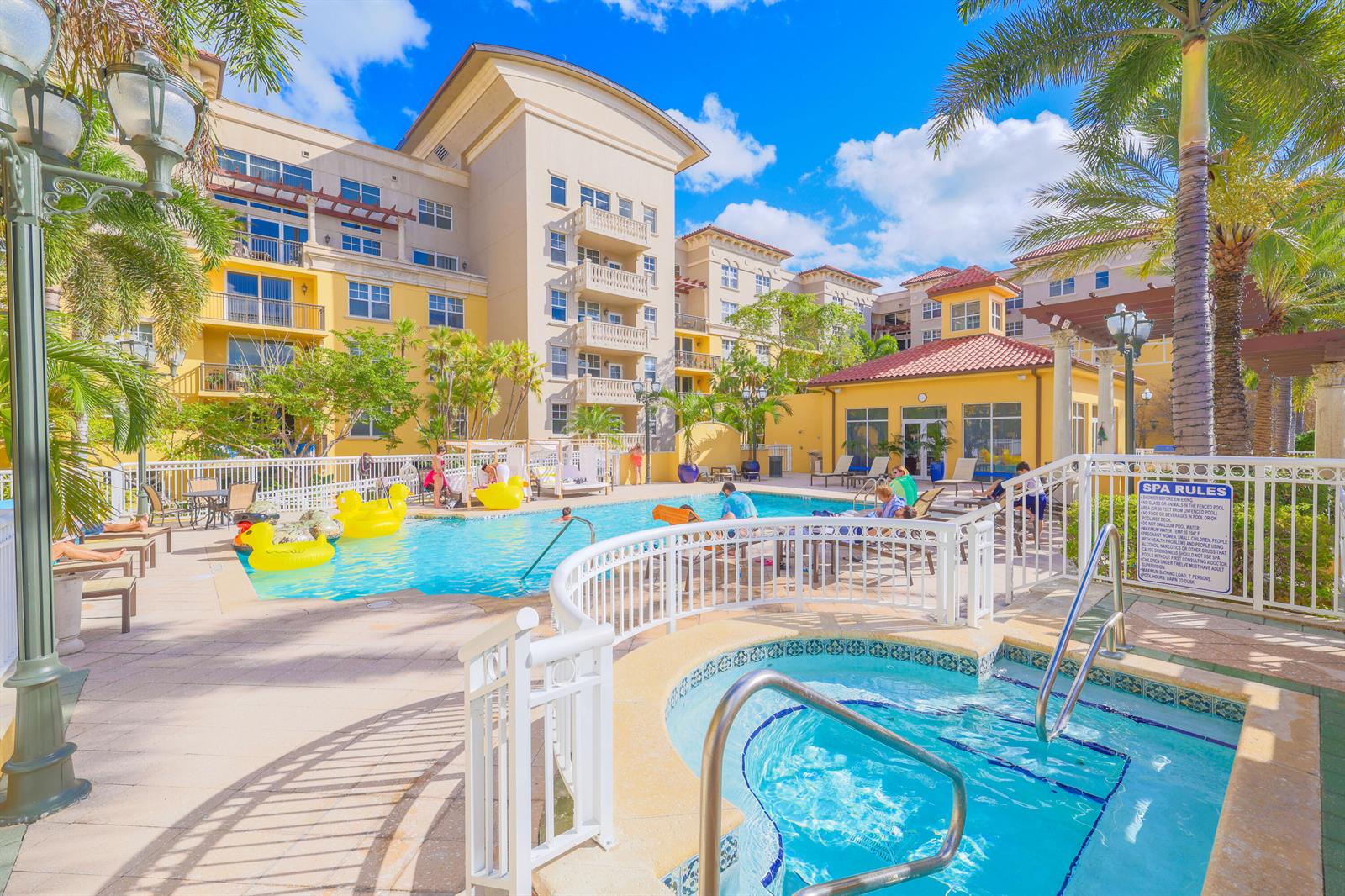 A swimming pool and hot tub are surrounded by a multi-story building and palm trees — 101 Plaza Real S # 829, Boca Raton FL 33432, BOCA RATON, FL