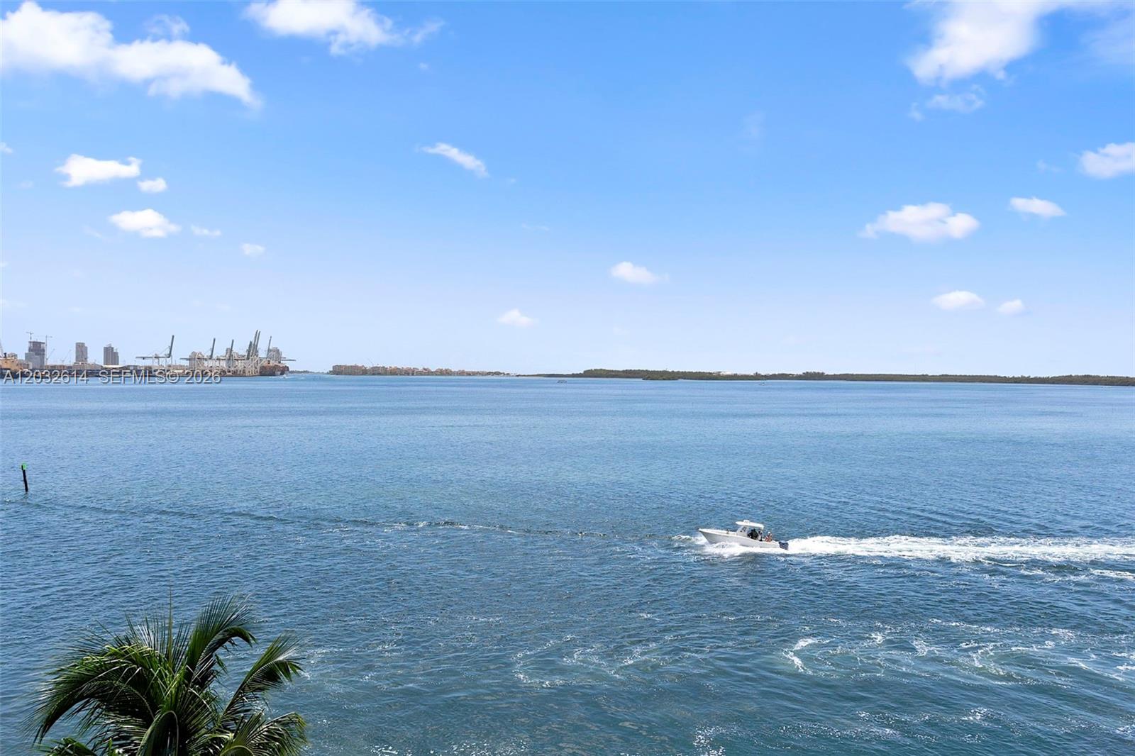 A small boat travels across a wide bay with a distant industrial port visible — 800 CLAUGHTON ISLAND DRIVE # 505, Miami FL 33131, MIAMI, FL