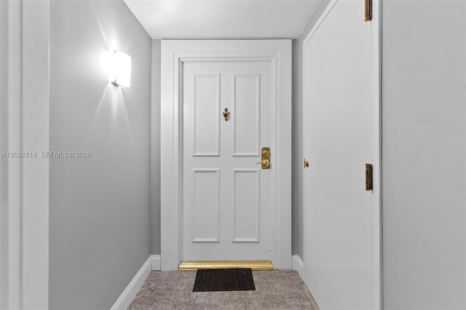 A white door with gold hardware is centered in a hallway with gray walls — 800 CLAUGHTON ISLAND DRIVE # 505, Miami FL 33131, MIAMI, FL