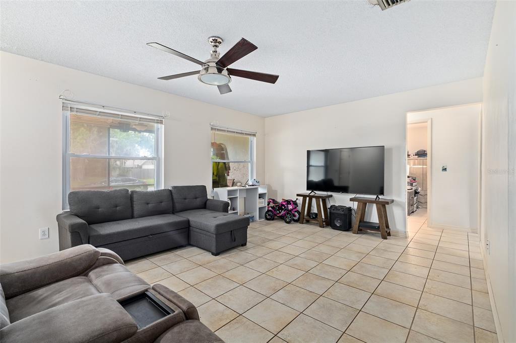 A living room features light tile flooring, a ceiling fan, and two gray sofas — 1218 MELLISA DRIVE, PORT ORANGE, FL