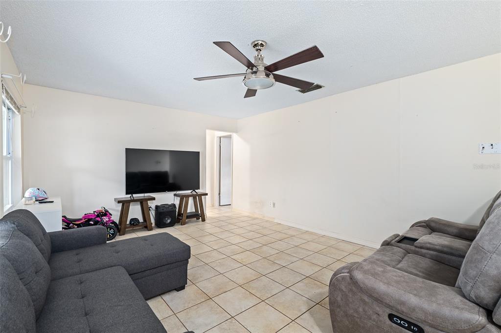 A kitchen features wood-grain cabinets, a breakfast bar with stools, and a black refrigerator — 1218 MELLISA DRIVE, PORT ORANGE, FL